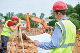 Fototapeta  - Construction workers on building area. Foreman with blueprint and surveyoor