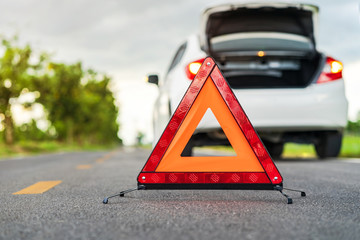 Problems car and a red triangle warning sign on the road