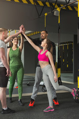 Wall Mural - Group of sporty people giving high-five at gym