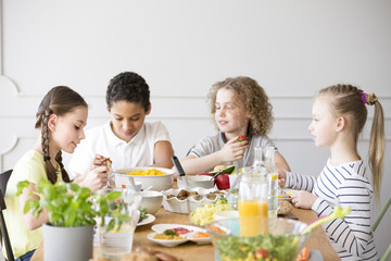 Wall Mural - Group of children eating healthy dinner at friend's home