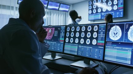 Over the Shoulder Shot of Senior Medical Scientist Working with CT Brain Scan Images on a Personal Computer in Laboratory. 