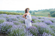 © LIGHTFIELD STUDIOS - attractive pregnant woman in white dress and straw hat standing at violet lavender field