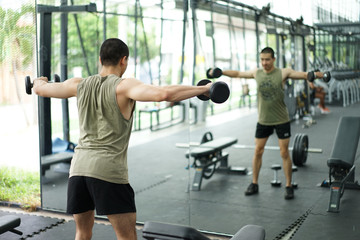 Asian men lifting dumbbells in the gym