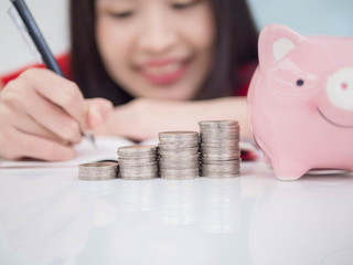 Woman Putting Coin In Piggy Bank.;