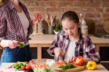 little cook. adolescent girl cutting vegetables and preparing dinner from fresh organic food ingredi