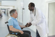 © JPC-PROD - African ,American,male doctor greeting recovering senior patient in wheelchair in hospital