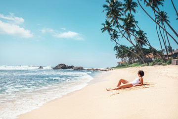 Wall Mural - Woman takes sunbath on tropical beach. Island paradise