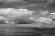 A black and white version of Storm Island beneath a bank of cumulus clouds