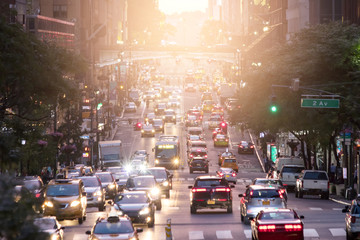 Crosstown traffic on 42nd Street in Midtown Manhattan New York City with sunlight in background