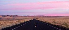 Flat Two Lane Blacktop Highway Heads Into The Pink Sunset
