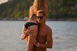 © Кристина Тримайлова - Happy couple in love boyfriend carrying his girlfriend in sea on a tropic beach from the back