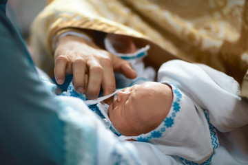 Newborn baby baptism by oil with hands of priest