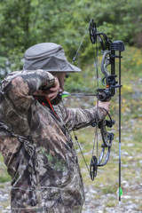 Wall Mural - A Man Wearing Camouflage Shooting a Compound Bow 