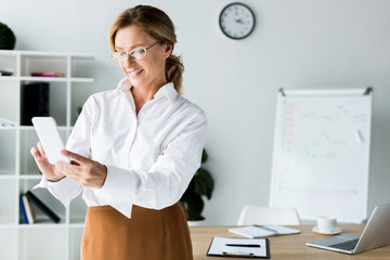 Wall Mural - smiling businesswoman taking selfie with smartphone in office