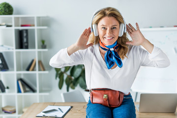 Wall Mural - attractive happy businesswoman listening music in headphones in office