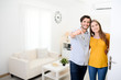 © W PRODUCTION - cheerful young couple man and woman welcome friends at open front door new student home apartment