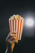 hand holding Popcorn in striped bucket isolated at the movie