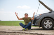 © snedorez - Picture of young man sitting next to broken car with open hood