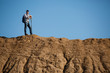 © snedorez - Photo of young tourist man with sticks for walking on hill against blue sky