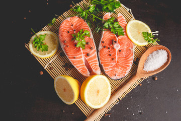 Two salmon steaks with lemon, pepper and salt. View from above.