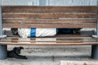 © Srdjan - Poor homeless man with his dog sleeping on the urban street in the city on the wooden bench. Homeless people concept.