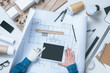 © LIGHTFIELD STUDIOS - cropped image of male architect with prosthetic arm using digital tablet over blueprint at table