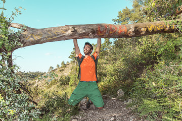 Guy hanging from a trunk in the woods