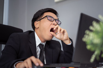 tired businessman using laptop and yawning