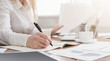 © Prostock-studio - Young successful woman writing notes while sitting in office