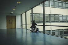 Handicapped Man On Wheelchair Looking Out Glass Pane