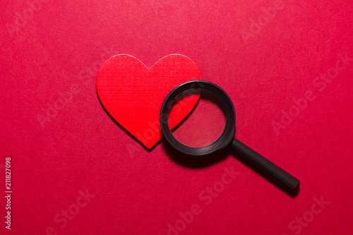 Red heart and magnifier. Looking for love cocept