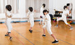 © JackF - Adults and teens wearing fencing uniform practicing with foil
