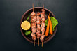 Baked Skewers of meat on a plate. On a wooden background. Top view. Copy space.