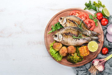 Baked fish with spices and vegetables. Carp On a wooden background. Top view. Copy space.