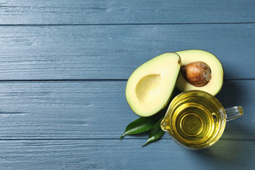 Gravy boat with oil and ripe fresh avocado on wooden table, top view