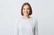 © timtimphoto - beautiful woman expresses happy emotions, has broad pleasant smile, wears white longsleeve and feels satisfied. Isolated over white background