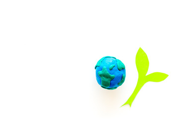 Planet, ecology. plastiline symbol of planet Earth globe and plant coutout on white background top view copy space