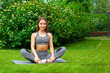 © Виталий Сова - Beautiful thin woman sportswoman  stretches legs before training on a yoga mat on a green lawn in the park on a summer day