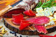 Sliced cured bresaola with spices and a sprig of rosemary.
