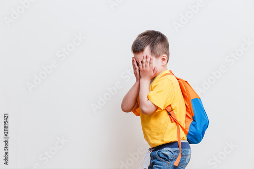 Fotografie, Obraz boy covers his face with his hands on a white background