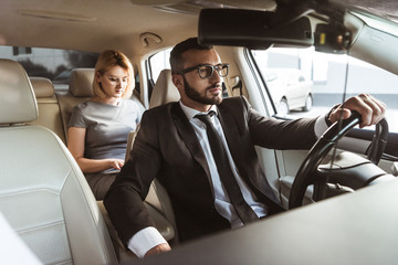 handsome driver and attractive businesswoman in car