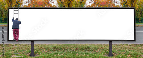 Fotografía Working man on very large commercial space billboard for urban advertisement on