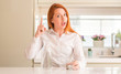 © Krakenimages.com - Thirsty redhead woman and glass of water surprised with an idea or question pointing finger with happy face, number one