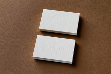 Wall Mural - Top view mockup of two white business cards stacks at brown craft paper background.