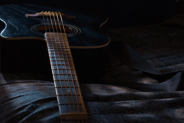 guitar laying in dark room with moonlight shining on it