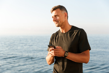 Wall Mural - Smiling sportsman using mobile phone