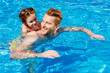 © LIGHTFIELD STUDIOS - handsome happy father swimming in pool and giving ride to daughter