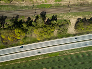 High-speed highway and railway, top view. Green field and blue sky.