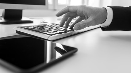 Wall Mural - monochrome image of businessman typing on a computer keyboard in office