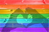 Fototapeta Tęcza - Shadows of hands forming a heart on colorful rainbow painted wood planks background, LGBTQ gay flag, LGBT pride and  love concept